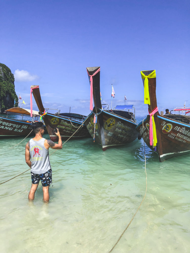 man taking pictures of longtail boats in krabi